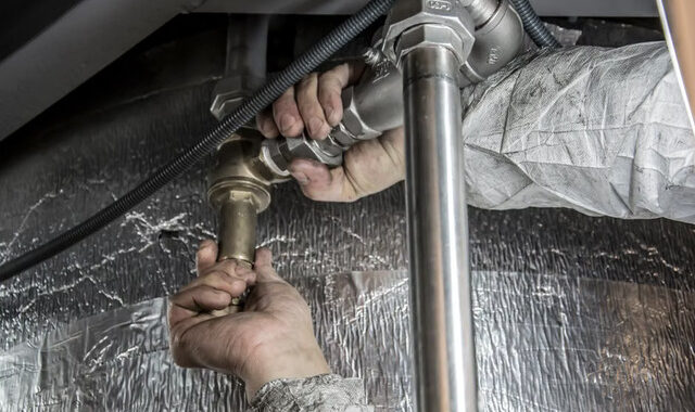 Mains d'un chauffagiste installant des raccords de tuyauterie avec précision lors d'une intervention à Toulouse