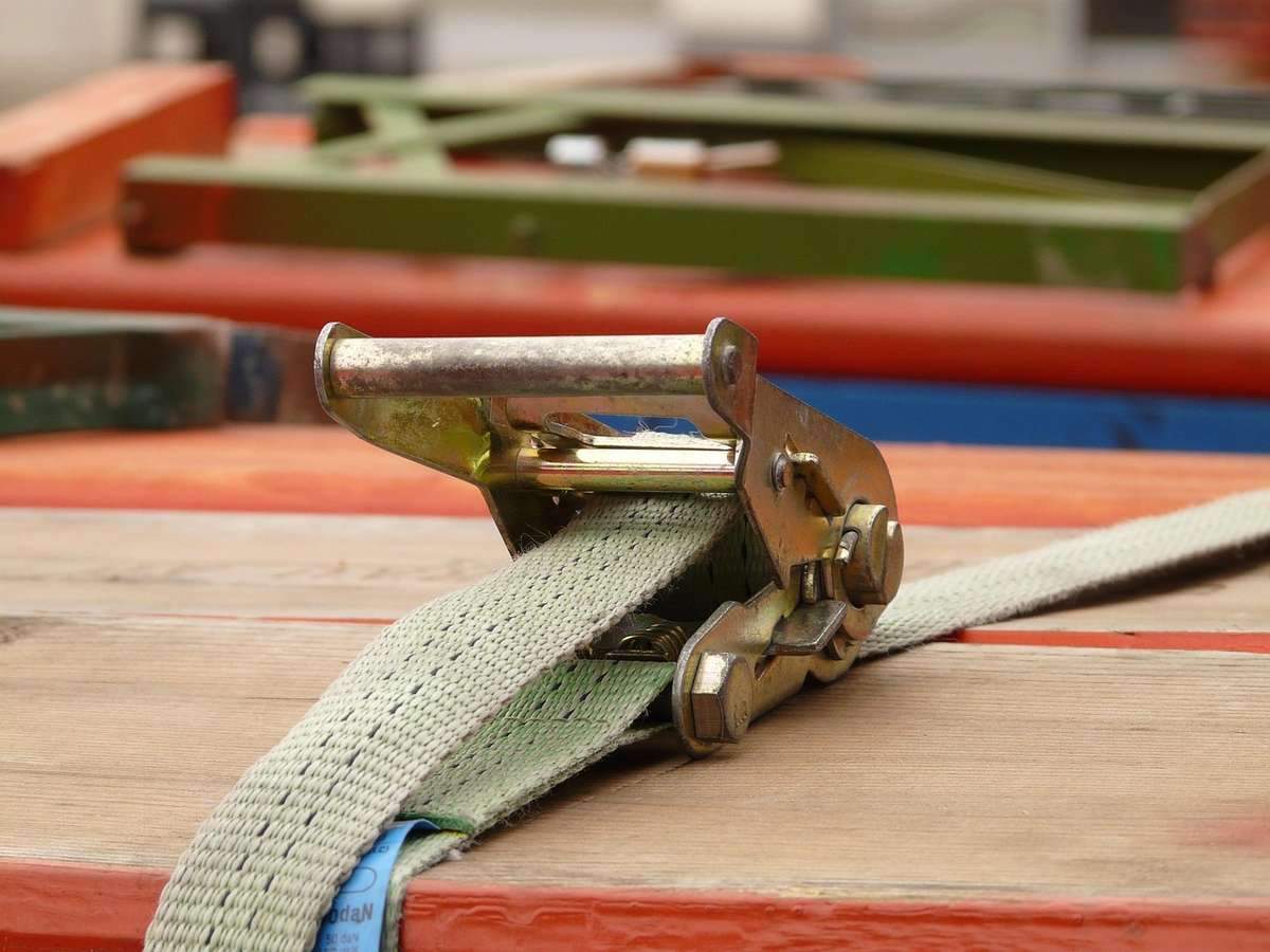 Sangle de fixation beige avec boucle métallique sur structure multicolore en bois et métal Sangle de fixation beige avec boucle métallique sur structure multicolore en bois et métal