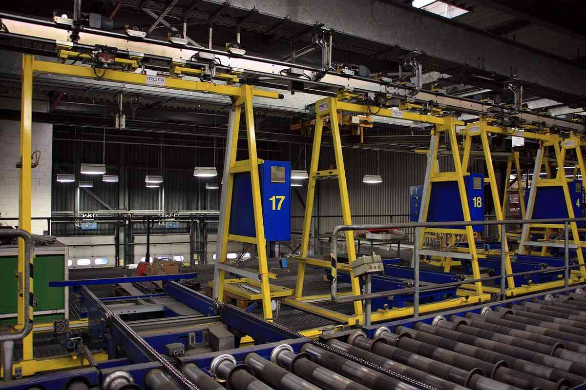 Grue mobile transportant des pièces sur un convoyeur dans une usine Grue mobile transportant des pièces sur un convoyeur dans une usine