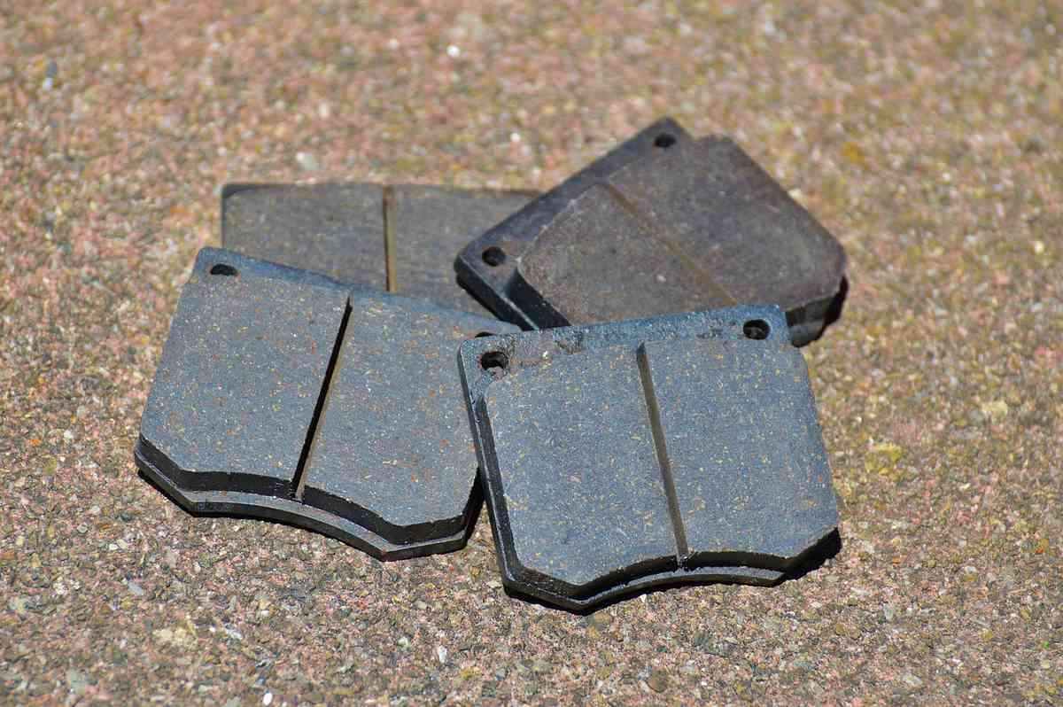 Quatre plaquettes de frein métalliques sur sol granuleux