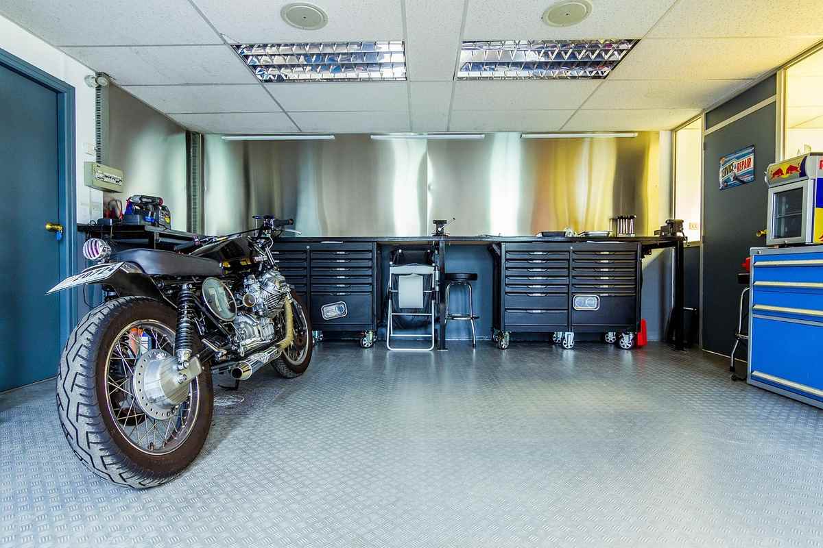 Un atelier avec une moto, des caissons à outils et un placard bleu