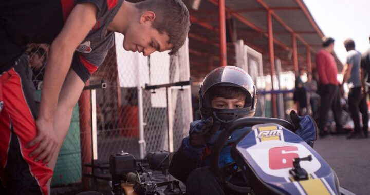 Un jeune pilote de karting reçoit l'aide d'un accompagnateur avant la course